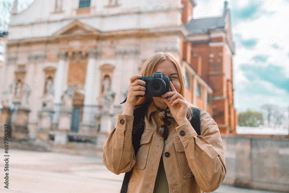 Attractive young female tourist woman takes a photo in the city during the day while traveling through the old town of Krakow in spring, Poland. High quality photo Attractive young female tourist woman takes a photo in the city during the day while traveling through the old town of Krakow in spring, Poland. High quality photo