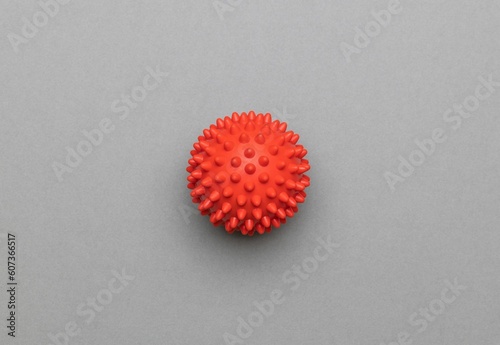 Close-up top view of a spikey red massage ball over the gray surface