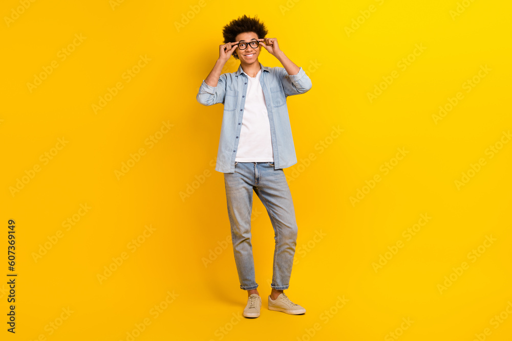 Full length photo of cheerful attractive person hands touch eyeglasses isolated on yellow color background Full length photo of cheerful attractive person hands touch eyeglasses isolated on yellow color background