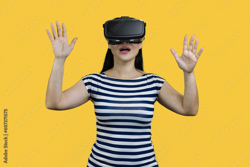 Portrait of a happy young smiling woman in vr headset with her hands up. Isolated on yellow. Portrait of a happy young smiling woman in vr headset with her hands up. Isolated on yellow.