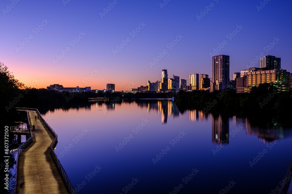 Beautiful view of TX skyline at blue hour from the boardwalk around Town Lake in Austin