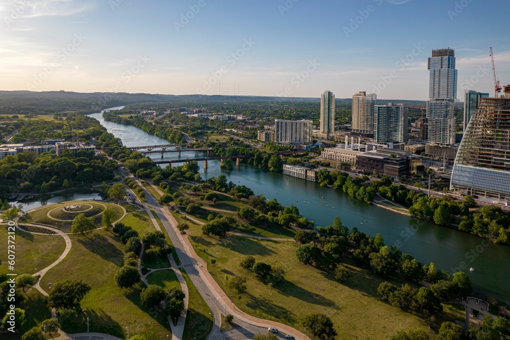 Drone shot of TX skyline with waterfront, greenery and blue cloudy sky in Austin city