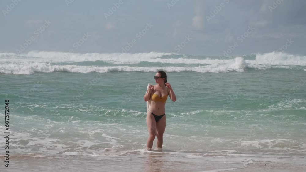 Attractive woman walking in the sea with splashing waves Attractive woman walking in the sea with splashing waves