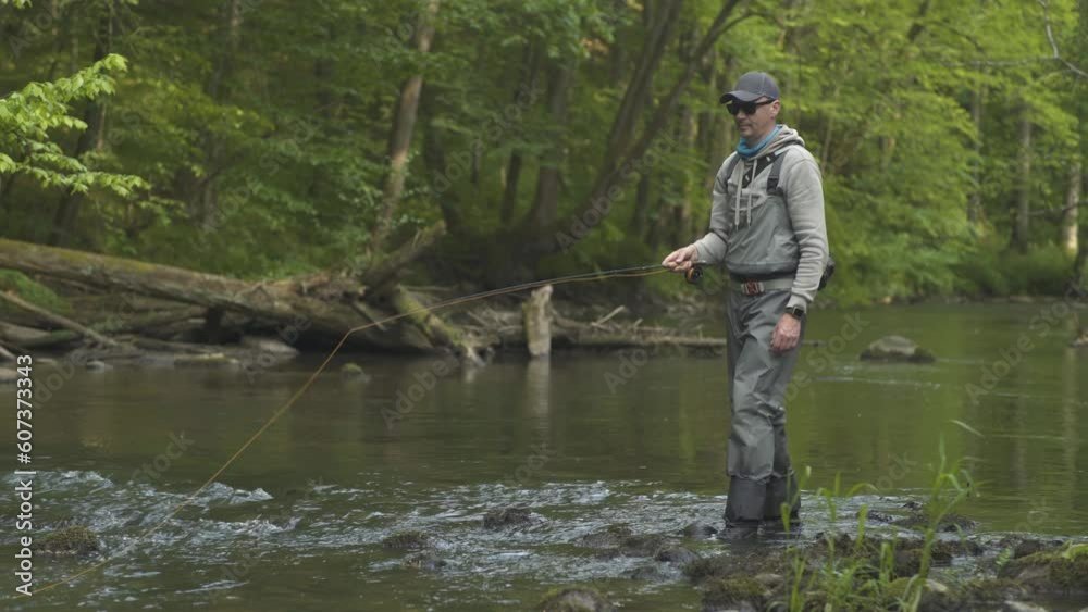 Fisherman catching brown trout on the fly standing in river. Fisherman catching brown trout on the fly standing in river.