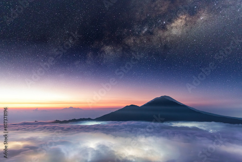 Sunrise from the top of Mount Batur in Bali Indonesia with Milky way on top and lighten up clouds below