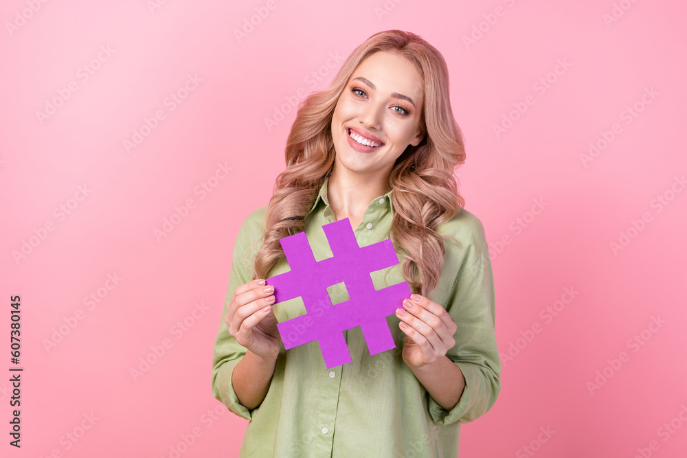 Photo of cute positive girl toothy smile arms hold paper hashtag symbol isolated on pink color background Photo of cute positive girl toothy smile arms hold paper hashtag symbol isolated on pink color background