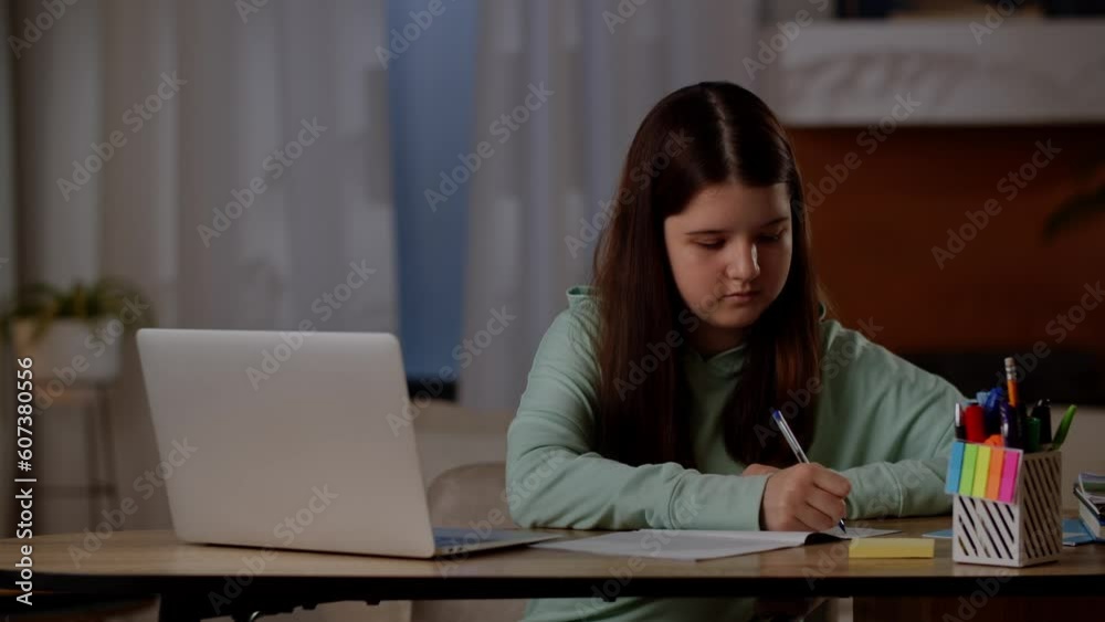 A little girl does her homework at the computer. The child is engaged in online learning at home with a laptop. A little girl does her homework at the computer. The child is engaged in online learning at home with a laptop.