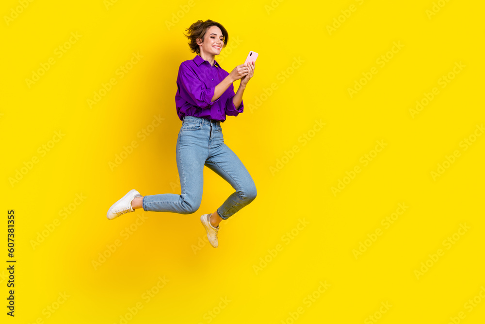 Full length photo of sweet cute lady wear violet shirt jumping chatting samsung iphone apple device isolated yellow color background