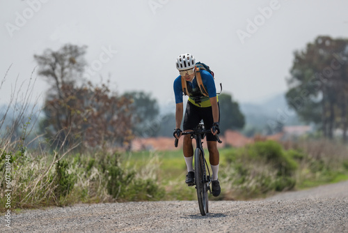 Asian man riding bicycle on gravel road