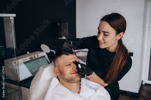 Attractive bearded man visiting aesthetic clinic, getting lips filler, closeup. Middle aged businessman having beauty injection at male spa salon. Face care, anti-aging treatment for men concept