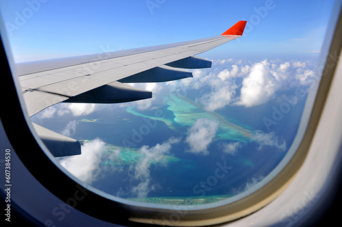 View of the islands from the porthole. View from above. Above the clouds. We fly by plane. Islands. Maldives. Beautiful landscapes. Aircraft wing. Islands from above. Ocean. Indian Ocean. In the cloud