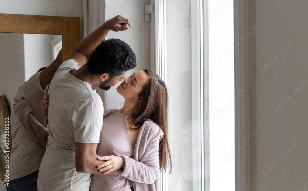 Multiethnic American couple embracing at home.