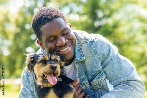 latin american man walking with his cute dog at sunny day in city park lawn on the grass