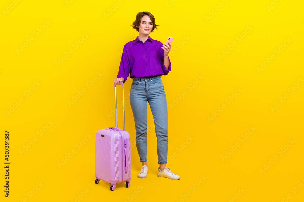Full body photo of attractive young woman device suitcase dressed stylish purple smart casual clothes isolated on yellow color background Full body photo of attractive young woman device suitcase dressed stylish purple smart casual clothes isolated on yellow color background
