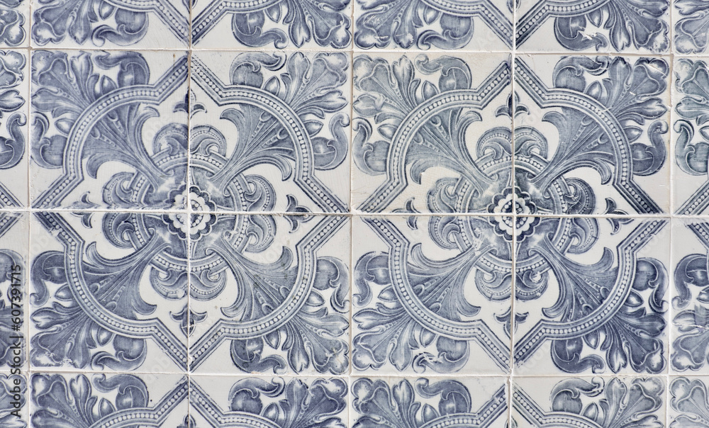 Vintage ceramic tiles of faded blue colour with floral repetitive ornate in Lisbon, Portugal. Authentic Portuguese tiling art. Faded grey photo