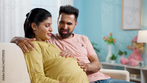 Happy Indian caring husband spending time with pregnant wife at home - concept of companionship, maternity love and family support