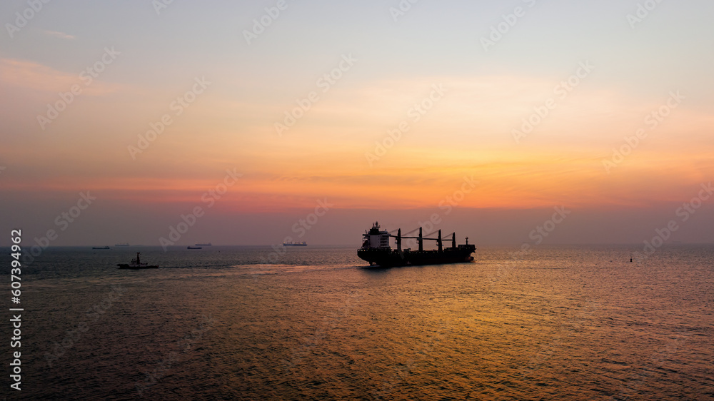 Seascape and silhouette container ship floating in sea and over the sunlight background