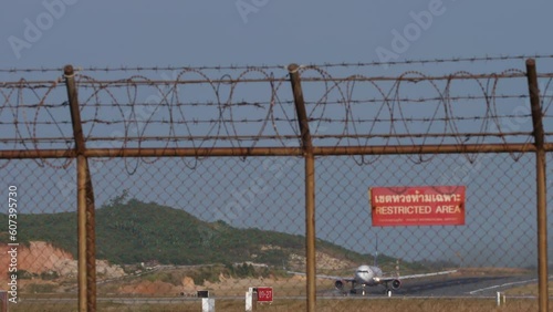 Wide boddy airliner taking off and climbing at Phuket Airport. Foreground plate restricted area photo