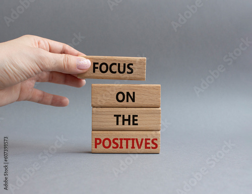 Focus on the Positives symbol. Concept word Focus on the Positives on wooden blocks. Beautiful grey background. Businessman hand. Business and Focus on the Positives concept. Copy space