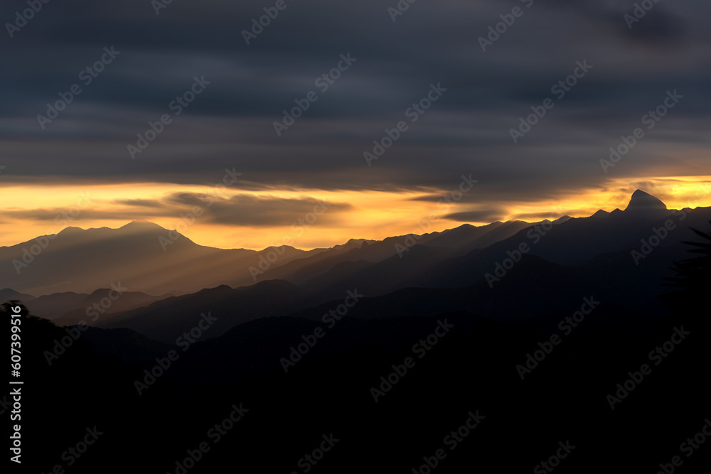 Layers of mountains bathed in orange light at sunset