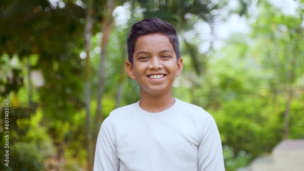 handheld shot of Happy smiling Indian young kid looking camera at park- concept of carefree or innocent childhood handheld shot of Happy smiling Indian young kid looking camera at park- concept of carefree or innocent childhood