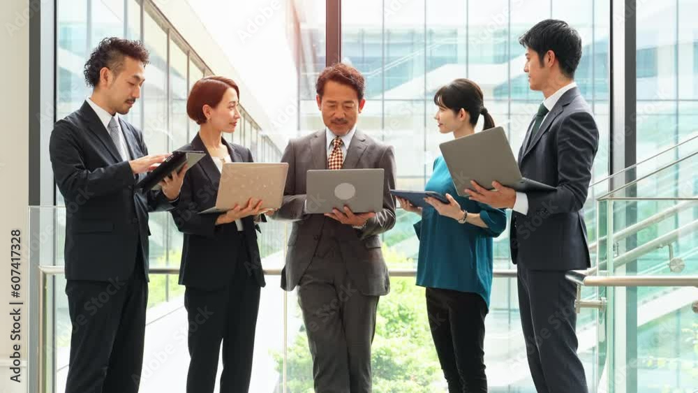 デジタルデバイスを持って打ち合わせするビジネスパーソンのグループ