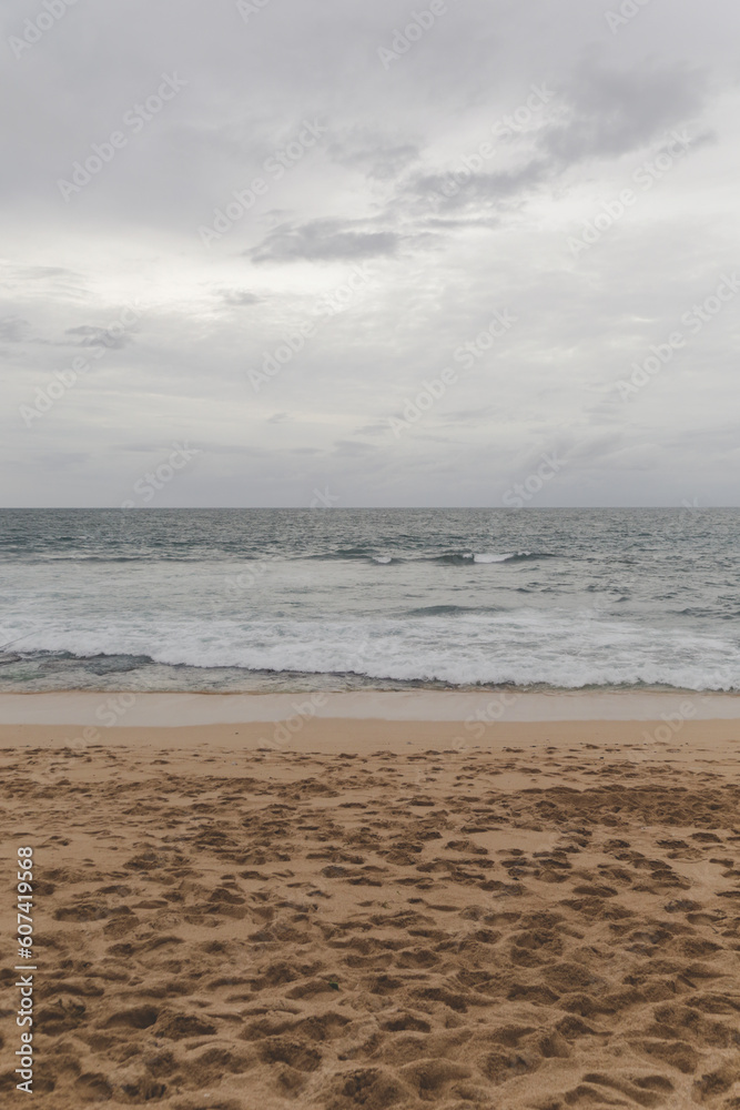Ocean waves break on empty sand beach during cloudy gloomy day Ocean waves break on empty sand beach during cloudy gloomy day