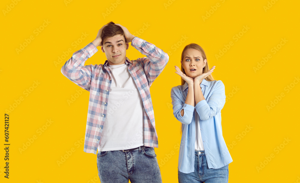 Portrait of two shocked people. Man and woman bewildered by unexpected situation. Young couple isolated on yellow background looking at something with scared surprised confused nervous face expression Portrait of two shocked people. Man and woman bewildered by unexpected situation. Young couple isolated on yellow background looking at something with scared surprised confused nervous face expression