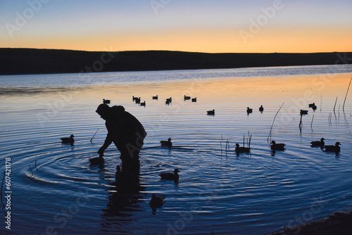 A waterfowl hunter setting decoys at sunrise