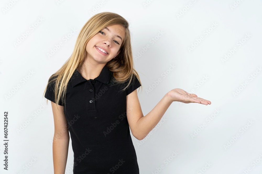 beautiful teen girl wearing black dress over white studio background smiling cheerful presenting and pointing with palm of hand looking at the camera. beautiful teen girl wearing black dress over white studio background smiling cheerful presenting and pointing with palm of hand looking at the camera.