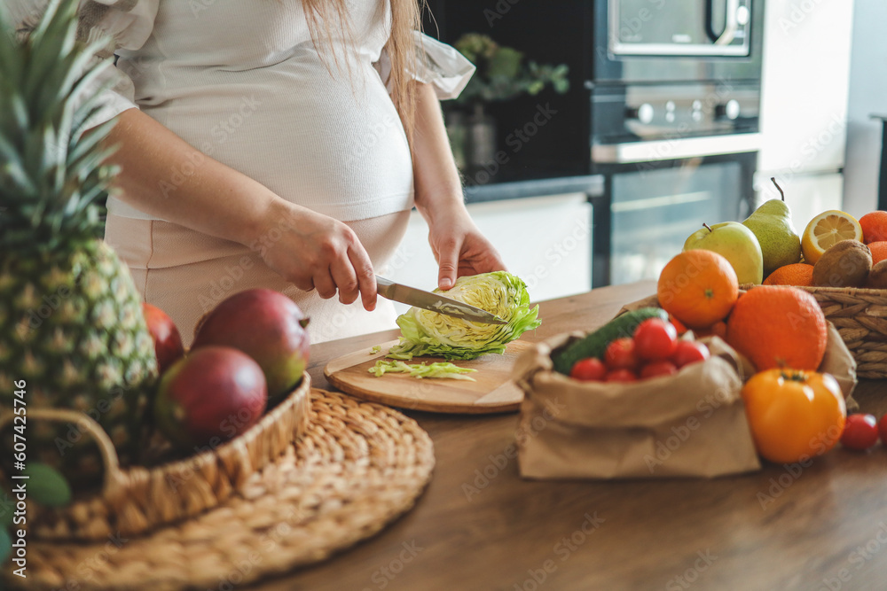 Pregnant woman making salad in her kitchen, healthcare