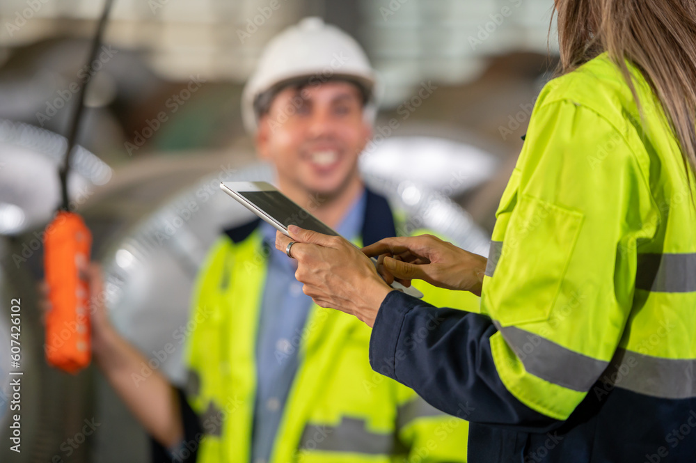 Obraz premium Factory apprenticeship. Woman mentor teaching man employee trainee operating machine look monitors and hand press control button process machinery. Leader foreman explaining engineer control machine