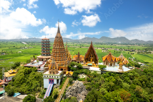 Top view of  Wat Tham Sua, chinese shrine temple on top hill with green rice fields and blue sky in Kanchanaburi Thailand photo