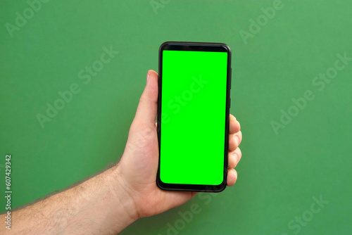 Young man hand use smartphone with green screen on green background. Gestures pack. Male hand touching, clicking, tapping swiping on black phone chroma key display. Close up Device. Modern Technology