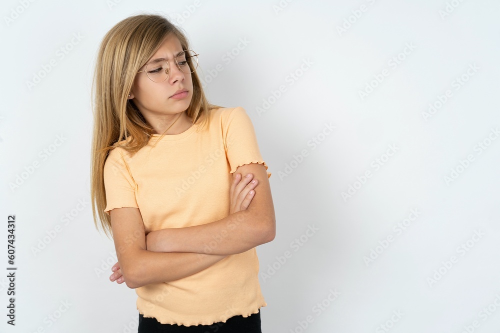 Φωτογραφία Image of upset beautiful caucasian teen girl wearing orange T-shirt over white wall with arms crossed
