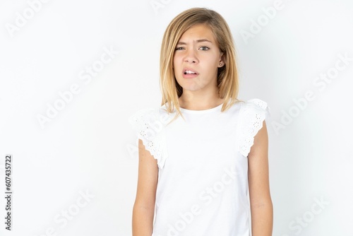 Fototapeta Portrait of dissatisfied beautiful caucasian teen girl wearing white T-shirt ove