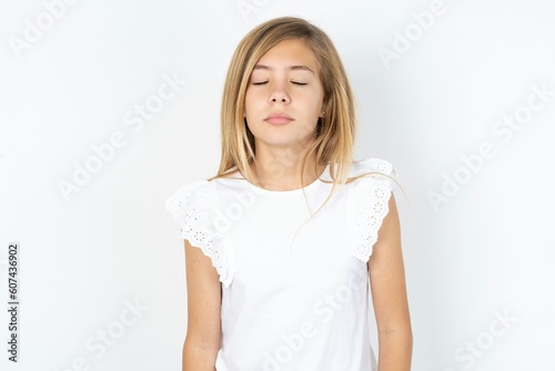 beautiful caucasian teen girl wearing white T-shirt over white wall nice-looking sweet charming cute attractive lovely winsome sweet peaceful closed eyes