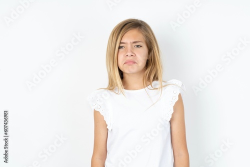 beautiful caucasian teen girl wearing white T-shirt over white wall depressed and worry for distress, crying angry and afraid. Sad expression.