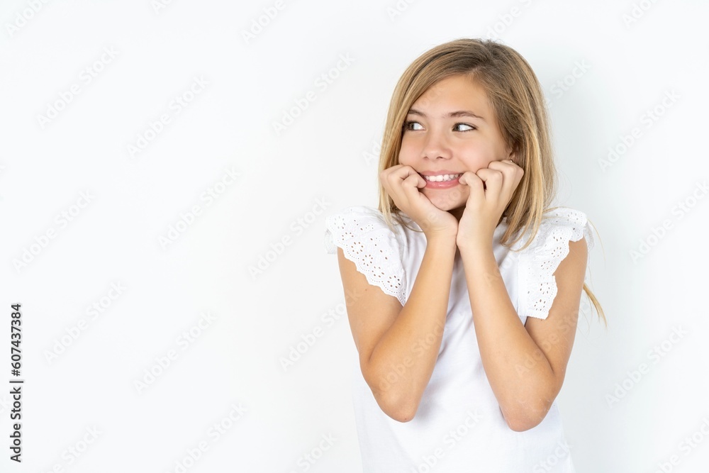 Terrified beautiful caucasian teen girl wearing white T-shirt over white wall looks empty space home alone moonless night Terrified beautiful caucasian teen girl wearing white T-shirt over white wall looks empty space home alone moonless night