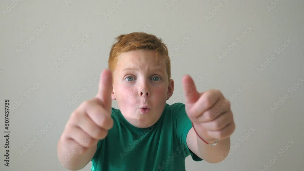 Portrait of happy red hair boy with freckles. Adorable handsome baby cheering success and showing thumbs up. Close up emotions of male child with joy expression on face. Slow motion Portrait of happy red hair boy with freckles. Adorable handsome baby cheering success and showing thumbs up. Close up emotions of male child with joy expression on face. Slow motion