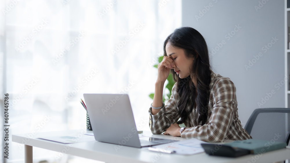 Young Asian businesswoman worried about problem at work and stressed with laptop computer at office. Young Asian businesswoman worried about problem at work and stressed with laptop computer at office.