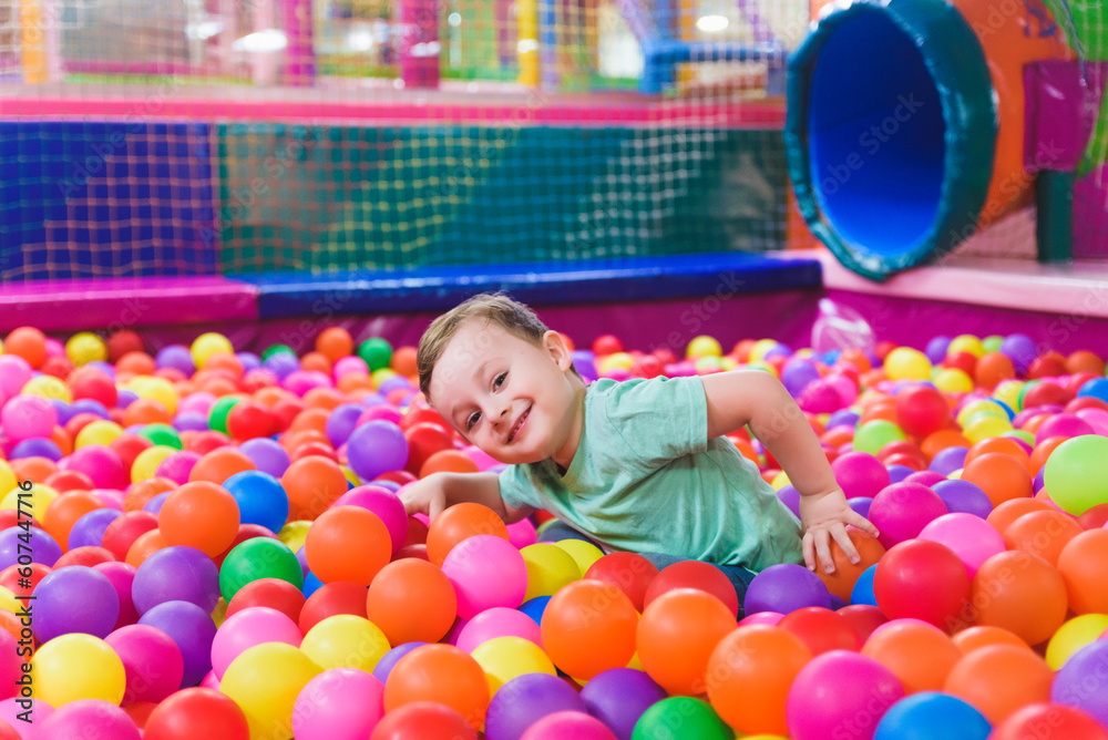 Obraz premium Portrait of three funny little kids playing in ball pit and enjoying time in childrens entertainment and play area, copy space