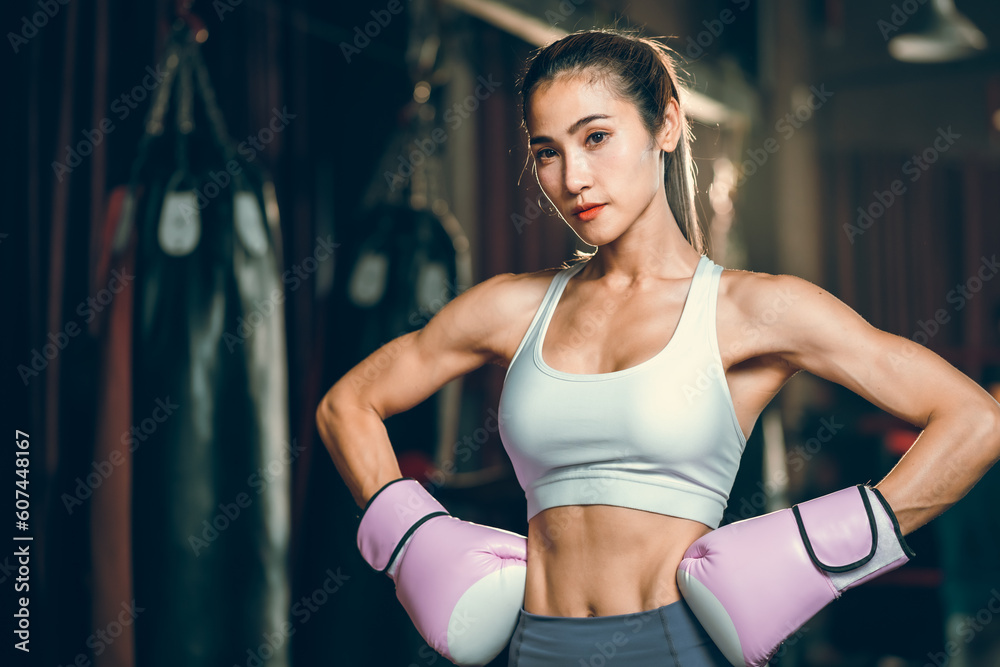 sporty athlete young Asian woman wearing sportswear and pink punching gloves practicing boxing martial arts. fit attractive female doing boxing at the fitness kickboxing gym, Portrait of female boxer