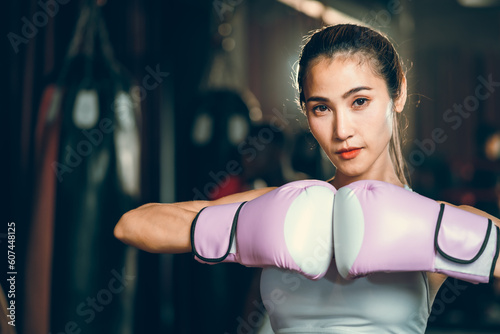 sporty athlete young Asian woman wearing sportswear and pink punching gloves practicing boxing martial arts. fit attractive female doing boxing at the fitness kickboxing gym, Portrait of female boxer