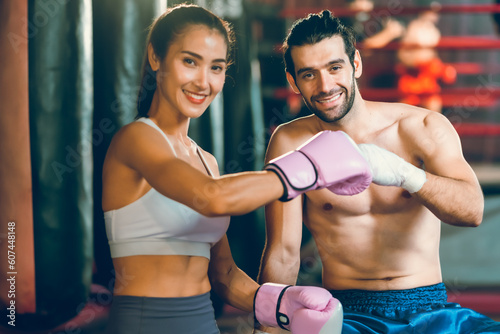 sporty athlete young Asian woman wearing sportswear and pink punching gloves practicing boxing martial arts. fit attractive female doing boxing at the fitness kickboxing gym, Portrait of female boxer © chokniti