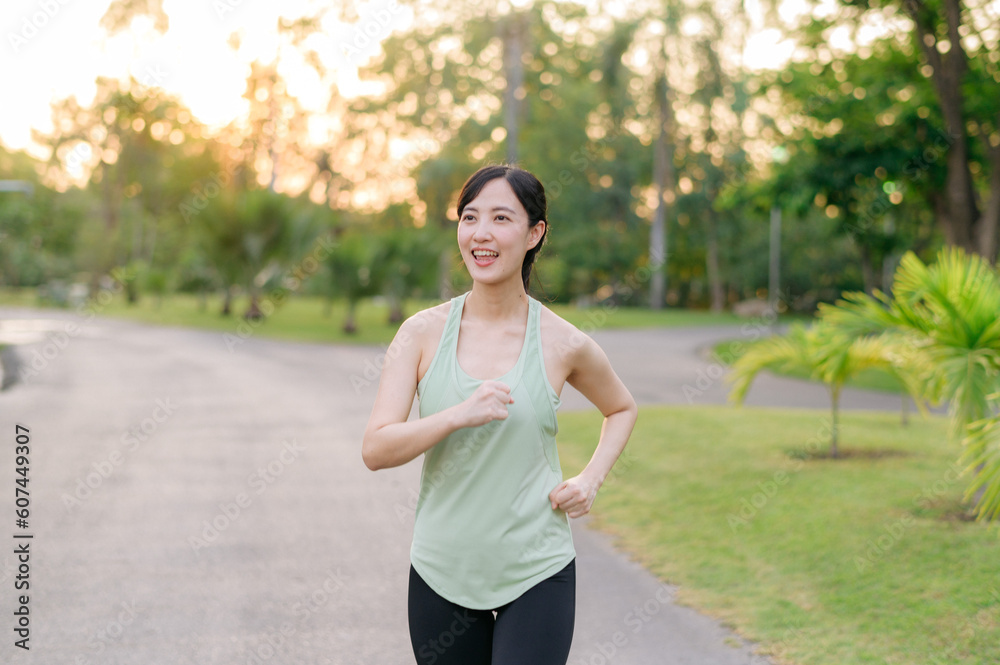 Fit Asian young woman jogging in park smiling happy running and enjoying a healthy outdoor lifestyle. Female jogger. Fitness runner girl in public park. healthy lifestyle and wellness being concept Fit Asian young woman jogging in park smiling happy running and enjoying a healthy outdoor lifestyle. Female jogger. Fitness runner girl in public park. healthy lifestyle and wellness being concept