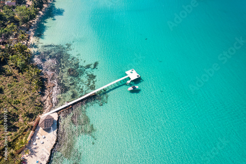 Beautiful turquoise sea beach and wooden pier, boat on coastline in sunny day
