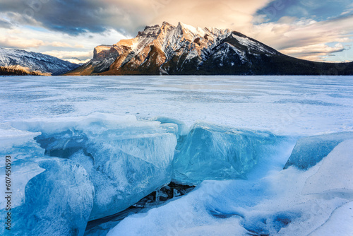 Frozen Lake Minnewanka with rocky mountains and cracked ice in winter