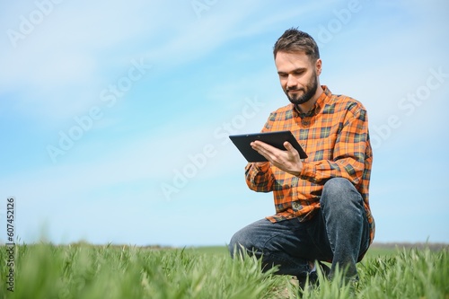 Portrait of farmer in wheat field. A handsome farmer or agronomist is working in the field