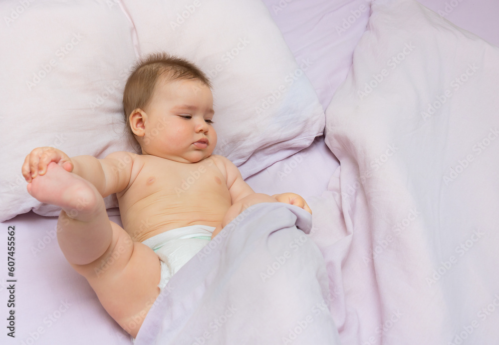 baby girl lies in bed and tries to free herself from under the covers baby girl lies in bed and tries to free herself from under the covers